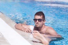 Retrato del jugo de consumición hermoso del hombre joven en la piscina fotografía de archivo libre de regalías Retrato del jugo de consumición hermoso del hombre joven en la piscina fotografía de archivo libre de regalías