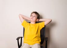 Retrato del muchacho adolescente feliz en la camiseta amarilla que se sienta en una silla Fotografía de archivo libre de regalías Retrato del muchacho adolescente feliz en la camiseta amarilla que se sienta en una silla Fotografía de archivo libre de regalías