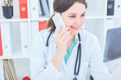 Retrato del primer de un doctor de sexo femenino sonriente de los jóvenes que mira el rayo de x y que consulta con el colega por imagen de archivo libre de regalías Retrato del primer de un doctor de sexo femenino sonriente de los jóvenes que mira el rayo de x y que consulta con el colega por imagen de archivo libre de regalías