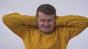 Retrato do homem caucasiano engraçado novo que fecha suas orelhas como se está receoso preocupado ouvir algo mau Pele do problema video estoque Retrato do homem caucasiano engraçado novo que fecha suas orelhas como se está receoso preocupado ouvir algo mau Pele do problema video estoque
