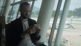 Retrato do homem de negócios novo que está usando seu smartphone no aeroporto filme Retrato do homem de negócios novo que está usando seu smartphone no aeroporto filme