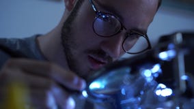 Retrato do homem farpado novo bem sucedido no funcionamento de vidros com um ferro de solda em seu lugar de trabalho Conceito do video estoque Retrato do homem farpado novo bem sucedido no funcionamento de vidros com um ferro de solda em seu lugar de trabalho Conceito do video estoque