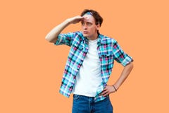Retrato do homem sério atento novo na posição quadriculado azul ocasional da faixa da camisa com mão na testa e na vista demasiad fotografia de stock Retrato do homem sério atento novo na posição quadriculado azul ocasional da faixa da camisa com mão na testa e na vista demasiad fotografia de stock