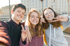 Retrato do menino adolescente de três amigos e duas das meninas que sorriem e que tomam um selfie fora Fundo da cidade, hora dour foto de stock Retrato do menino adolescente de três amigos e duas das meninas que sorriem e que tomam um selfie fora Fundo da cidade, hora dour foto de stock