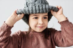 Retrato encantador de la niña caucásica que juega con el suéter gris caliente del sombrero del invierno, de la sonrisa y el lleva imágenes de archivo libres de regalías Retrato encantador de la niña caucásica que juega con el suéter gris caliente del sombrero del invierno, de la sonrisa y el lleva imágenes de archivo libres de regalías