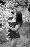 Retrato preto e branco de uma jovem mulher que guarda uma refeição matinal da árvore de ameixa de florescência no jardim, sorrind fotos de stock Retrato preto e branco de uma jovem mulher que guarda uma refeição matinal da árvore de ameixa de florescência no jardim, sorrind fotos de stock