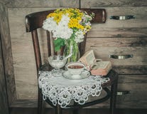 Retro Stoel met Bloemen in een Vaas, een Oud Gebedboek en een Kop thee royalty-vrije stock foto's Retro Stoel met Bloemen in een Vaas, een Oud Gebedboek en een Kop thee royalty-vrije stock foto's