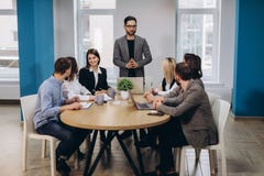 Reunião masculina do diretor empresarial com os trabalhadores de escritório, dando sentidos no escritório moderno à moda imagens de stock royalty free Reunião masculina do diretor empresarial com os trabalhadores de escritório, dando sentidos no escritório moderno à moda imagens de stock royalty free