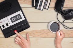 Revolution concept. Retro cassette tape recorder with headphones and cassettes lying on wooden table. View of woman`s hands pressi royalty free stock image Revolution concept. Retro cassette tape recorder with headphones and cassettes lying on wooden table. View of woman`s hands pressi royalty free stock image