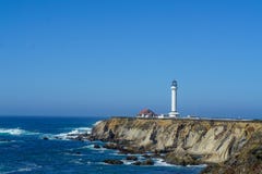 Lighthouse on a cliff on the ocean with waves on a beautiful summer day stock photography Lighthouse on a cliff on the ocean with waves on a beautiful summer day stock photography