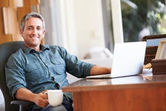 Rijpe Spaanse Mens die Laptop op Bureau thuis met behulp van royalty-vrije stock afbeeldingen Rijpe Spaanse Mens die Laptop op Bureau thuis met behulp van royalty-vrije stock afbeeldingen