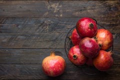 Ripe juicy organic bright red pomegranates in metal wicker basket on reclaimed plank barn wood background. Fall produce harvest royalty free stock image Ripe juicy organic bright red pomegranates in metal wicker basket on reclaimed plank barn wood background. Fall produce harvest royalty free stock image