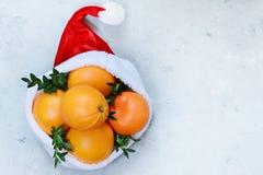 Ripe Oranges In The Hat Of Santa Claus With Boxwood Plant On A Blue Background. Festive Mood, Christmas And New Year. Stock Photography