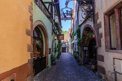 RIQUEWIHR, ФРАНЦИЯ - 17-ОЕ ИЮЛЯ 2017: Живописная улица с традиционными красочными домами в деревне Riquewihr на эльзасском винном стоковые фото RIQUEWIHR, ФРАНЦИЯ - 17-ОЕ ИЮЛЯ 2017: Живописная улица с традиционными красочными домами в деревне Riquewihr на эльзасском винном стоковые фото