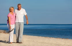 Rire de marche de couples supérieurs heureux sur une plage photographie stock Rire de marche de couples supérieurs heureux sur une plage photographie stock