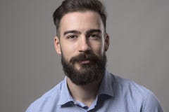 Ritratto alto vicino di orizzontale di giovane uomo alla moda barbuto di affari in camicia blu che esamina macchina fotografica Immagini Stock Ritratto alto vicino di orizzontale di giovane uomo alla moda barbuto di affari in camicia blu che esamina macchina fotografica Immagini Stock