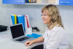 Ritratto del medico specialista sul lavoro, esaminando computer portatile, funzionante fotografia stock Ritratto del medico specialista sul lavoro, esaminando computer portatile, funzionante fotografia stock