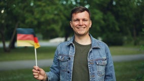 Ritratto del movimento lento della bandiera ufficiale d'ondeggiamento turistica tedesca allegra della Germania, sorridendo ed esa stock footage Ritratto del movimento lento della bandiera ufficiale d'ondeggiamento turistica tedesca allegra della Germania, sorridendo ed esa stock footage