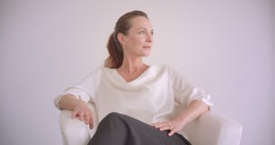 Ritratto del primo piano della femmina castana caucasica anziana che si siede nella poltrona che esamina macchina fotografica che Ritratto del primo piano della femmina castana caucasica anziana che si siede nella poltrona che esamina macchina fotografica che