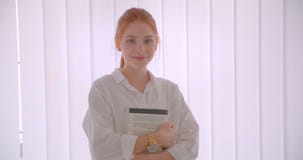 Ritratto del primo piano di giovane studentessa graziosa della testarossa che tiene un libro che esamina condizione della macchin stock footage Ritratto del primo piano di giovane studentessa graziosa della testarossa che tiene un libro che esamina condizione della macchin stock footage