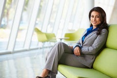 Ritratto della donna di affari che si siede sul sofà in ufficio moderno immagini stock libere da diritti Ritratto della donna di affari che si siede sul sofà in ufficio moderno immagini stock libere da diritti