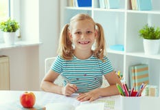 Ritratto della ragazza sveglia della scuola che si siede alla tavola bianca all'aula leggera immagini stock libere da diritti Ritratto della ragazza sveglia della scuola che si siede alla tavola bianca all'aula leggera immagini stock libere da diritti