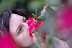 Ritratto di bello giovane individuo, bruna eccentrica, il suo naso attaccato in profondità in rose rosse fragranti fotografia stock Ritratto di bello giovane individuo, bruna eccentrica, il suo naso attaccato in profondità in rose rosse fragranti fotografia stock