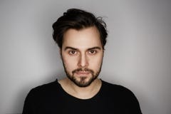 Ritratto di giovane uomo bello di modo in maglietta che bilancia mentre stando sul fondo grigio vuoto orizzontale fotografie stock libere da diritti Ritratto di giovane uomo bello di modo in maglietta che bilancia mentre stando sul fondo grigio vuoto orizzontale fotografie stock libere da diritti