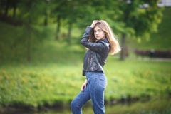 Ritratto di piccola bella ragazza alla moda del bambino in blue jeans e bomber nel parco della città sul fondo verde della forest fotografia stock Ritratto di piccola bella ragazza alla moda del bambino in blue jeans e bomber nel parco della città sul fondo verde della forest fotografia stock