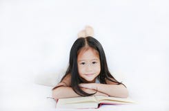 Ritratto di piccola ragazza asiatica sveglia del bambino che legge un libro che si trova sul fondo bianco fotografie stock libere da diritti Ritratto di piccola ragazza asiatica sveglia del bambino che legge un libro che si trova sul fondo bianco fotografie stock libere da diritti