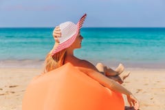Ritratto di stile di vita di estate della ragazza graziosa che si siede sul sofà gonfiabile arancio sulla spiaggia dell'isola tro fotografie stock Ritratto di stile di vita di estate della ragazza graziosa che si siede sul sofà gonfiabile arancio sulla spiaggia dell'isola tro fotografie stock