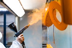Rivestimento della polvere delle parti di metallo Una donna in un vestito protettivo spruzza la pittura della polvere da una pist immagine stock Rivestimento della polvere delle parti di metallo Una donna in un vestito protettivo spruzza la pittura della polvere da una pist immagine stock