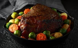 Roasted beef with honey glazed vegetables, served in cast iron vintage pan. festive dinner royalty free stock photo Roasted beef with honey glazed vegetables, served in cast iron vintage pan. festive dinner royalty free stock photo