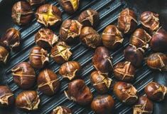 Roasted chestnuts over black cast iron grilling pan surface stock photography Roasted chestnuts over black cast iron grilling pan surface stock photography