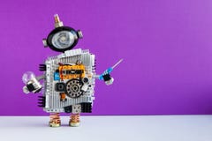 Robot electrician with light bulb screwdriver on violet wall gray floor background. copy space royalty free stock photos Robot electrician with light bulb screwdriver on violet wall gray floor background. copy space royalty free stock photos