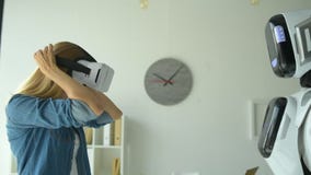 Robotic maskin som ger flickavirtuell verklighethörlurar med mikrofon stock video Robotic maskin som ger flickavirtuell verklighethörlurar med mikrofon stock video