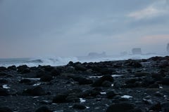 Rochas pretas com as ondas despedaçando-se no fundo na praia de Reynisfjara em Islândia imagens de stock Rochas pretas com as ondas despedaçando-se no fundo na praia de Reynisfjara em Islândia imagens de stock