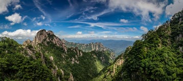 Rocky peaks and old pine trees cover the mountains under a bright blue sky with whispy clouds in Huangshan China stock photos Rocky peaks and old pine trees cover the mountains under a bright blue sky with whispy clouds in Huangshan China stock photos