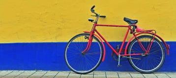 Rode fiets voor de gele en blauwe muur stock afbeeldingen Rode fiets voor de gele en blauwe muur stock afbeeldingen