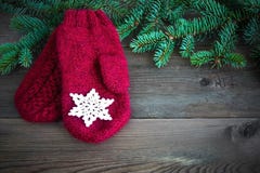 Rode wolvuisthandschoenen met met katoen gehaakte sneeuwvlok dichtbij de groene boom van het Kerstmisbont op de rustieke houten a stock fotografie Rode wolvuisthandschoenen met met katoen gehaakte sneeuwvlok dichtbij de groene boom van het Kerstmisbont op de rustieke houten a stock fotografie