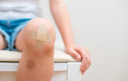 Rodilla del niño con el vendaje adhesivo imagenes de archivo Rodilla del niño con el vendaje adhesivo imagenes de archivo