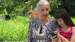 Rodzina z telefonicznym telefonem Szczęśliwa wnuczka pokazuje babci telefon komórkowego Rodzina z telefonem komórkowym w naturze zdjęcie wideo Rodzina z telefonicznym telefonem Szczęśliwa wnuczka pokazuje babci telefon komórkowego Rodzina z telefonem komórkowym w naturze zdjęcie wideo