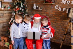 Roliga pojkevänner förhindrar Santa Claus från att beställa gåvor på l arkivbild Roliga pojkevänner förhindrar Santa Claus från att beställa gåvor på l arkivbild