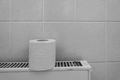 A roll of toilet paper stands on a radiator stock images A roll of toilet paper stands on a radiator stock images