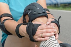 Rollerskater женщины кладя на пусковые площадки протектора колена на ее ноге стоковые изображения Rollerskater женщины кладя на пусковые площадки протектора колена на ее ноге стоковые изображения