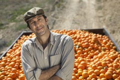 Rolnik Z ręki Krzyżującą pozycją Przeciw przyczepie pomarańcze obraz stock Rolnik Z ręki Krzyżującą pozycją Przeciw przyczepie pomarańcze obraz stock