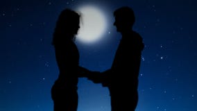 Romantic couple holding hands and kissing under starry night sky, relationships