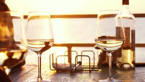 A romantic dinner in summer on a beach at sunset with two glasses of white wine and a bottle of the wine royalty free stock photo A romantic dinner in summer on a beach at sunset with two glasses of white wine and a bottle of the wine royalty free stock photo