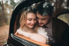 Romantic fairytale wedding couple kissing and embracing in pine forest near retro car. Royalty Free Stock Photo Romantic fairytale wedding couple kissing and embracing in pine forest near retro car. Royalty Free Stock Photo