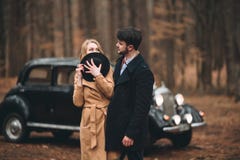 Romantic fairytale wedding couple kissing and embracing in pine forest near retro car. Stock Photos Romantic fairytale wedding couple kissing and embracing in pine forest near retro car. Stock Photos